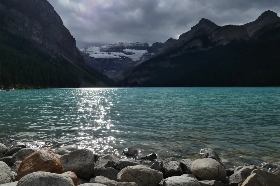 Turquoise lake framed by dark mountain slopes and a distant glacier